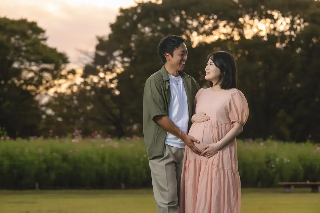 夕暮れの公園で寄り添うマタニティの夫婦