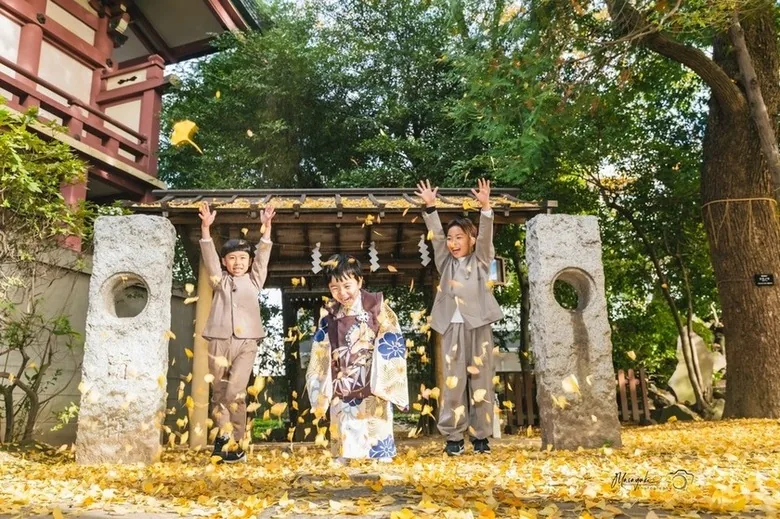 銀杏の境内で両手を上げる家族