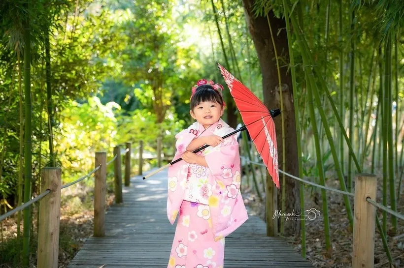 竹林の小道で赤い和傘を持つ着物姿の女の子